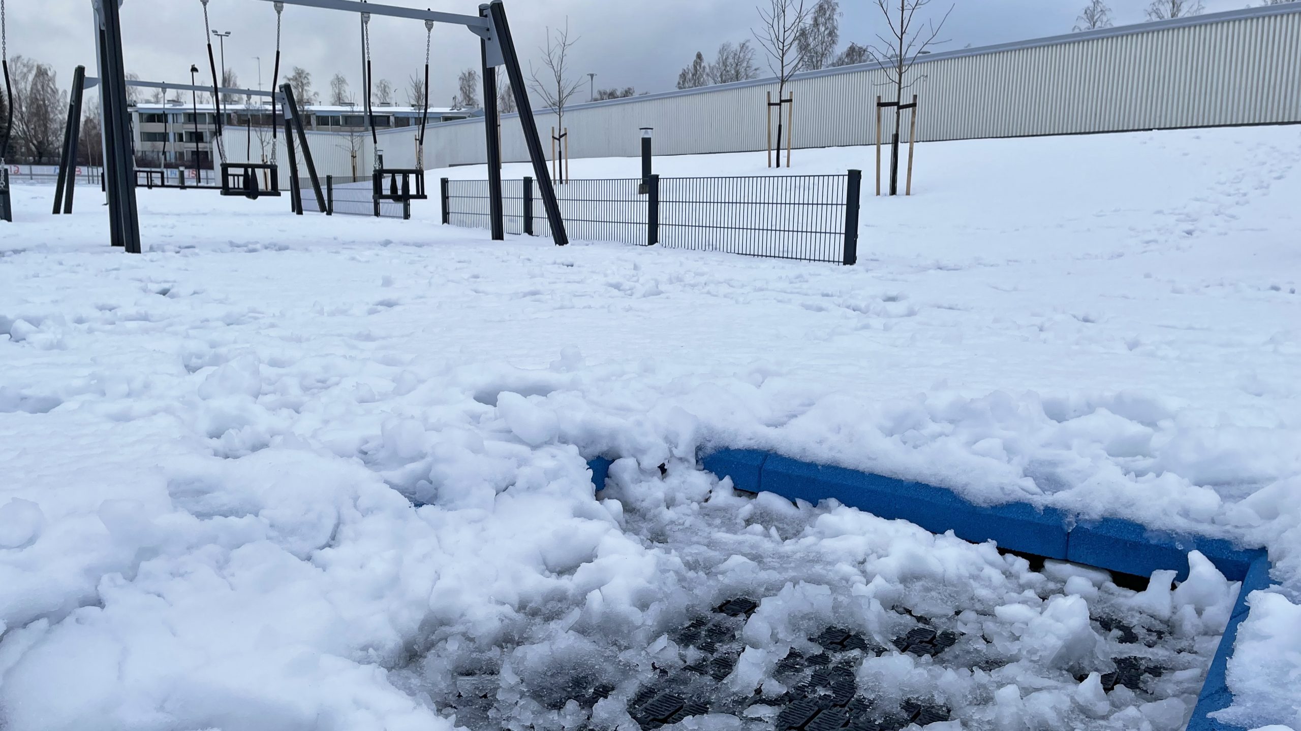 Päiväkodin piha-aluetta. Trampolini ja keinuja.