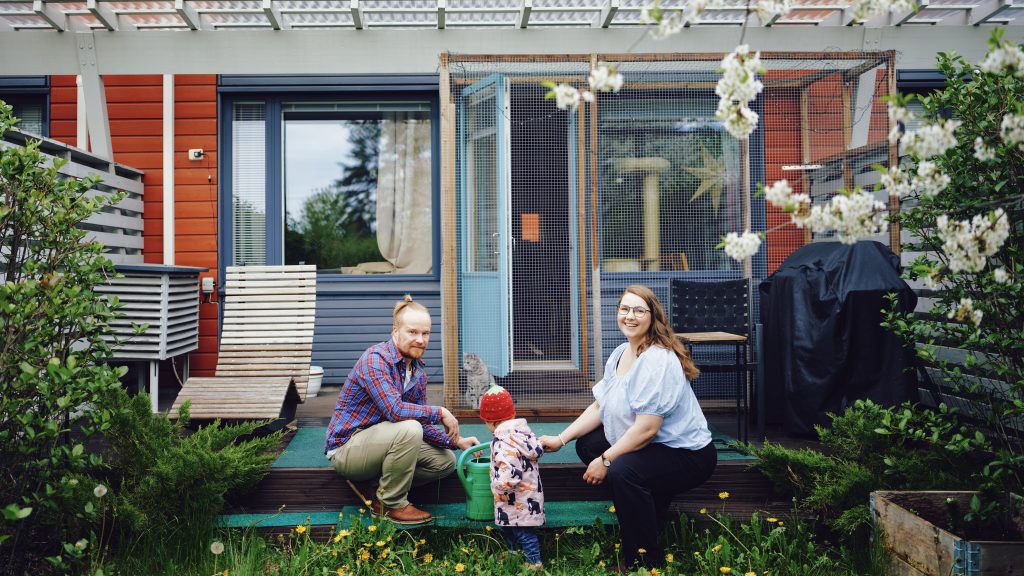 Taru och Eetu Sairanen med sitt barn på sin lägenhets lummiga gård.