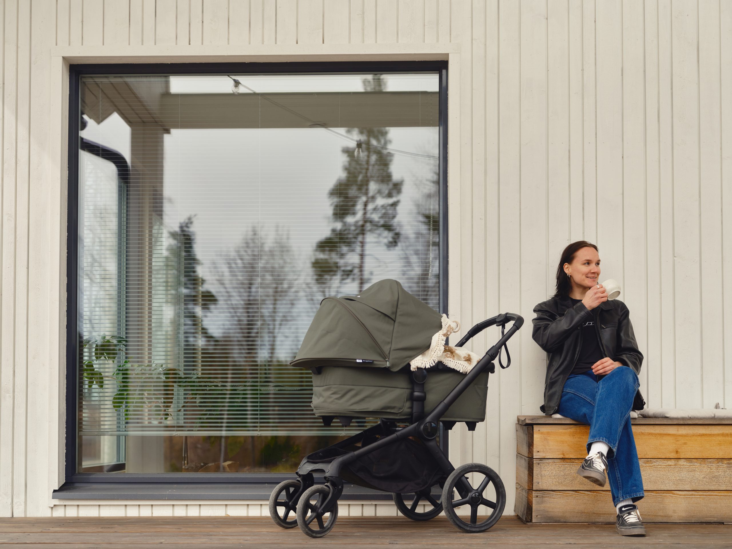 Senni Salminen som sitter på sitt eget terrass med barnvagnen.