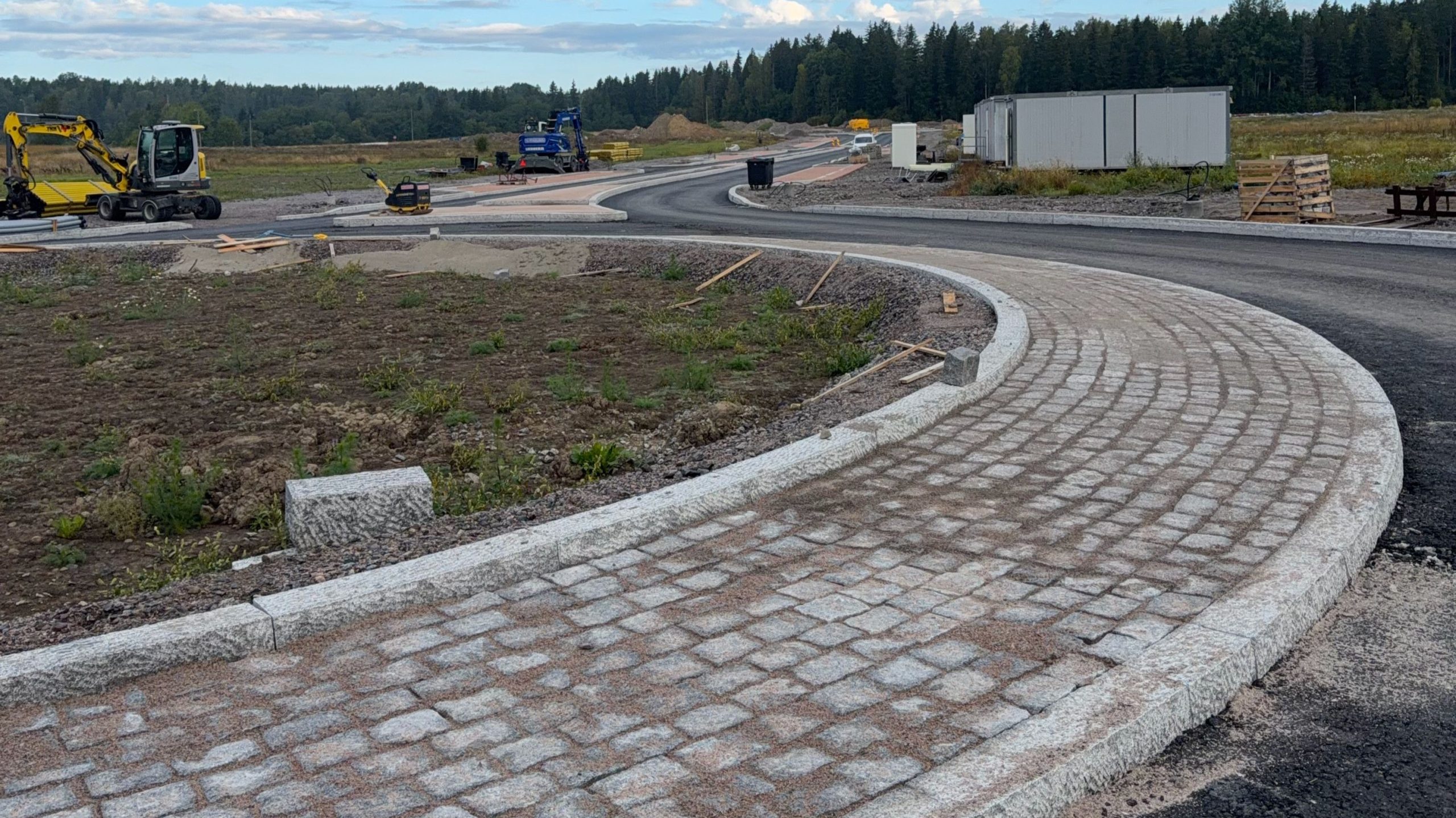 Gatans ytkonstruktioner byggs på byggarbetsplatsen. Asfalt, stensättningar, arbetsmaskiner.