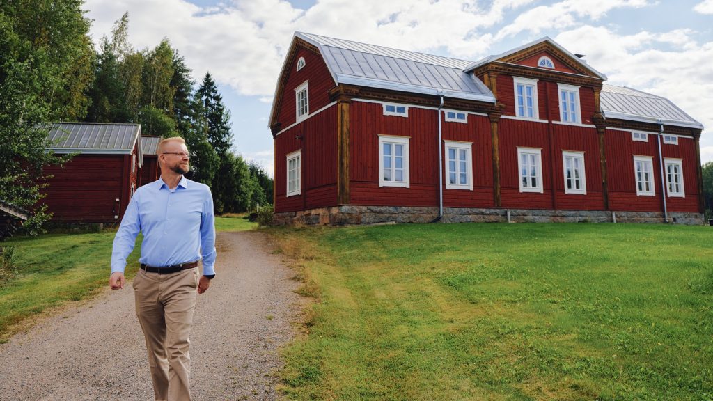 Jari Vesanen går utanför Varpulas timmerhus.